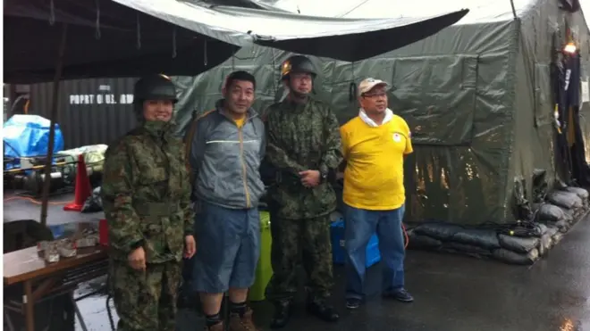 Miguel Kamiunten (de cinza), junto a militares nos abrigos após terremoto de Tohoku em 2011