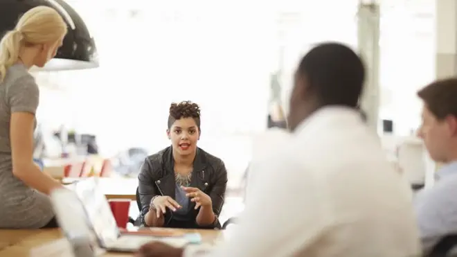 Mulher jovem liderando uma reunião