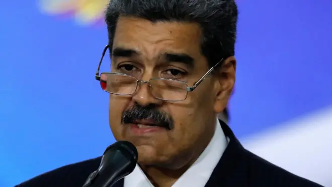 Imagem de Nicólas Maduro, um homem venezuelano idoso de cabelo preto, bigode e óculos