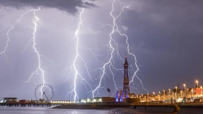 Raios durante a noite perto de baía e orla de cidade