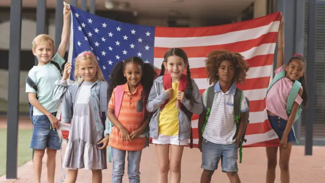 Crianças americanas em frente a uma bandeira dos EUA