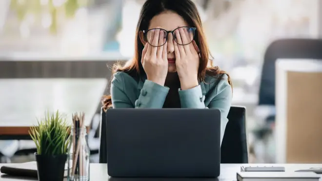 Mulher com sono em frente a computador