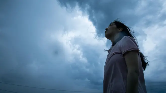 Uma mulher olhando para nuvens de tempestade