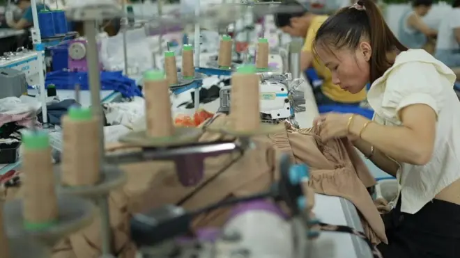 A woman hunched over a  sewing machine, making an outfit in a factory that supplies to Shein.