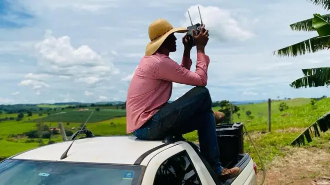 Gustavo em cima de carro usando controle de drone