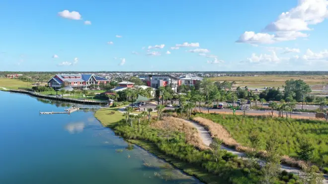 Foto mostra cidade com muito verde sob céu azul