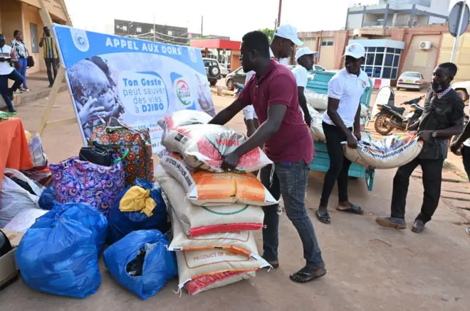 Des habitants chargent des sacs de riz, de vêtements et de biens divers collectés par des associations caritatives locales pour les habitants de Djibo.