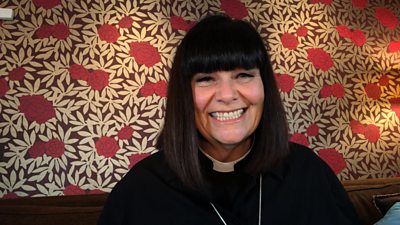 Dawn French as the Vicar of Dibley smiling in front of some flowery wallpaper