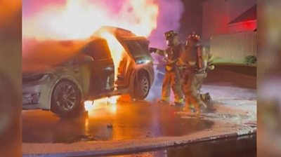 Fire fighters putting out fire after Tesla sets alight