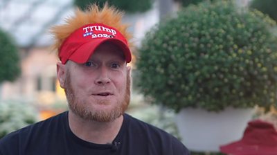 Greg Smith sitting inside plant shop wearing red Trump 2024 hat