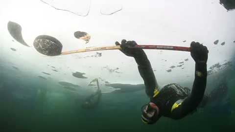 Underwater ice hockey player