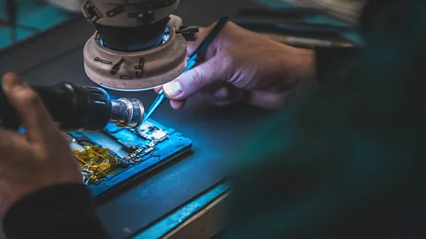 A technician repairing a mobile phone (Credit: Alamy)