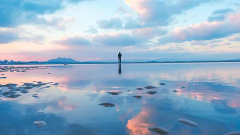 Fukutsu Sea Mirror with person standing on beach (Credit: Hikarinomichi DMO Fukutsu)