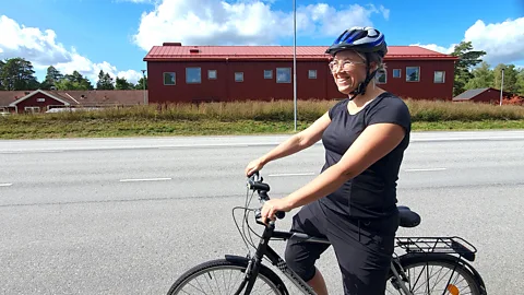 Matilda Welin wearing a helmet on her bike on a road with a red building in the background (Credit: Matilda Welin)