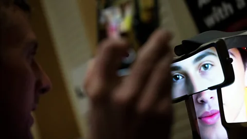 A man talks to a screen showing an AI companion's face (Credit: Getty Images)