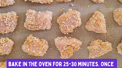 Raw chicken pieces covered in cereal crumbs on a baking tray.