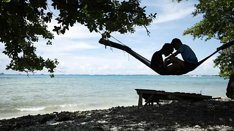 Two children sit in a hammock on beach in Tuvalu (Credit: Getty Images)