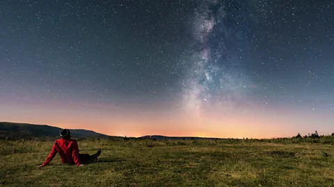 Man lying on the grass watching the Milky Way (Credit: Getty Images)