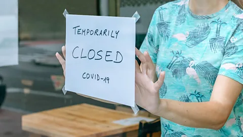 File image of woman placing a 'Closed' sign on a cafe