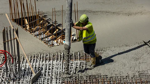 Getty Images A construction worker pouring concrete foundations (Credit: Getty Images)