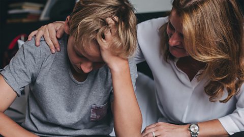 A mother comforts her upset son