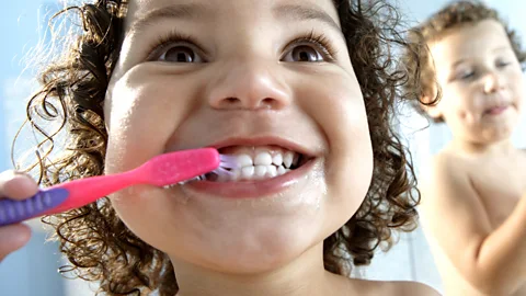 Getty Images Children brush their teeth using a manual plastic toothbrush (Credit: Getty Images)