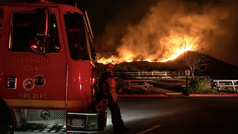 Getty Images An LA County firefighter watches flames from the Franklin Fire in the Malibu Mountains (Credit: Getty Images)