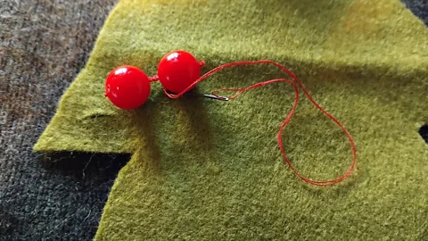 Duncan Stanworth I attach baubles to my felt tree and decorate the cutouts with green and yellow thread (Credit: Duncan Stanworth)