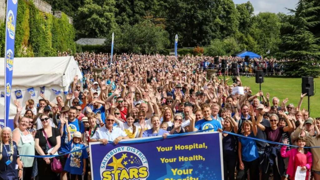 A large crowd of people taking part in the Stars Appeal walk. They are all gathered, looking at the camera and cheering. The people at the front are holding a Stars Appeal banner.