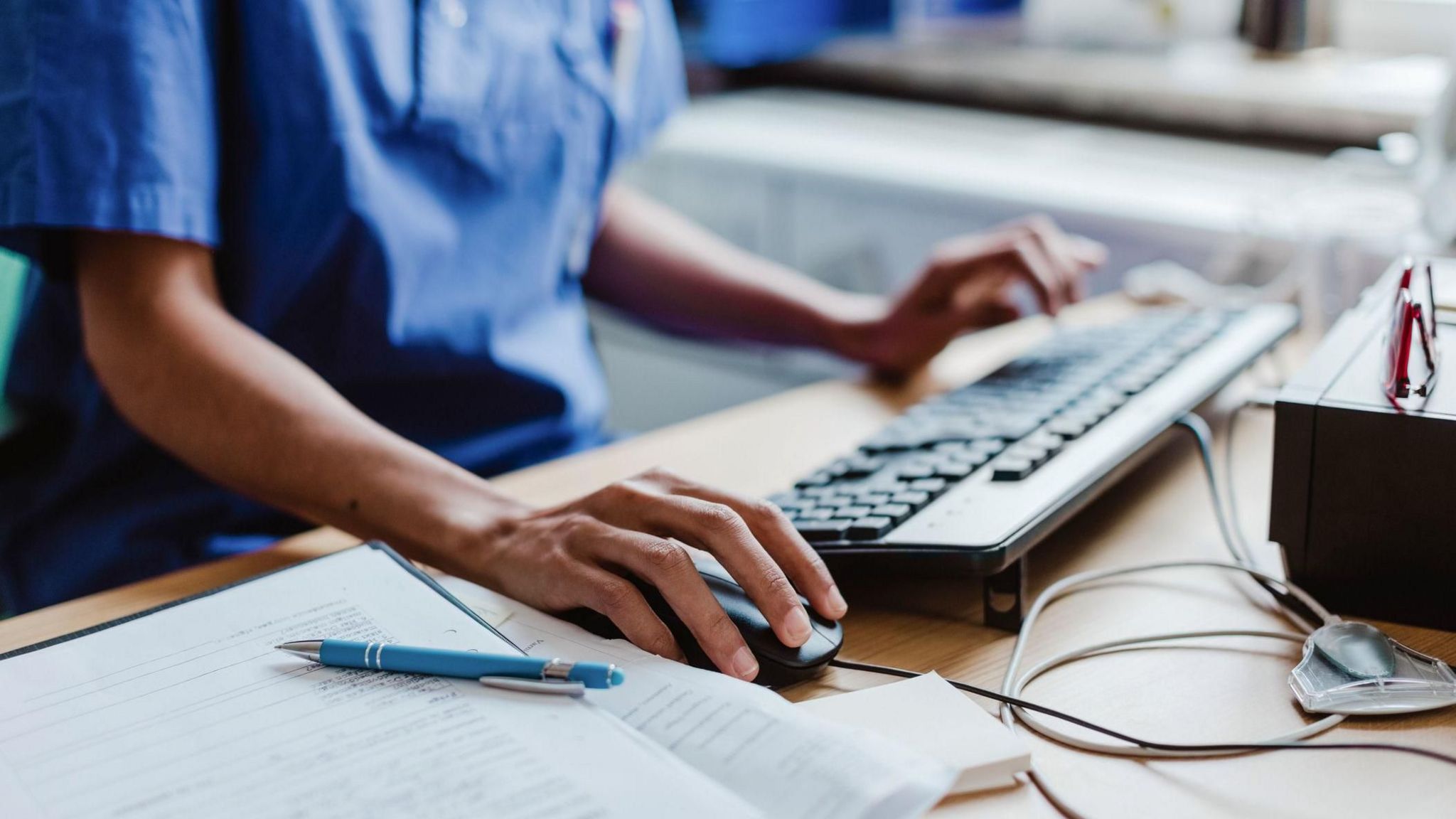 Hands of an NHS staff member working on a computer