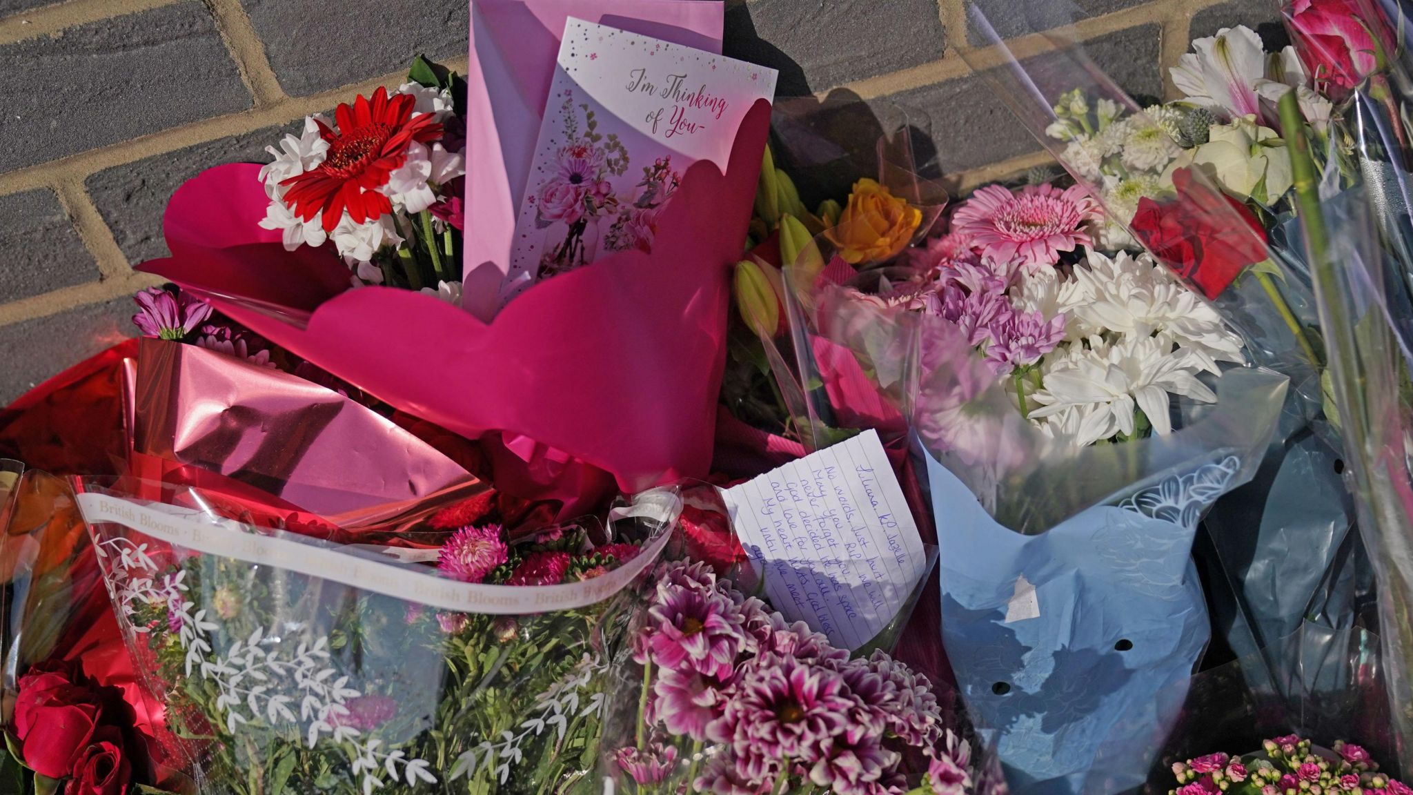 Brightly-coloured bunches of flowers, a Thinking of You card and a handwritten note