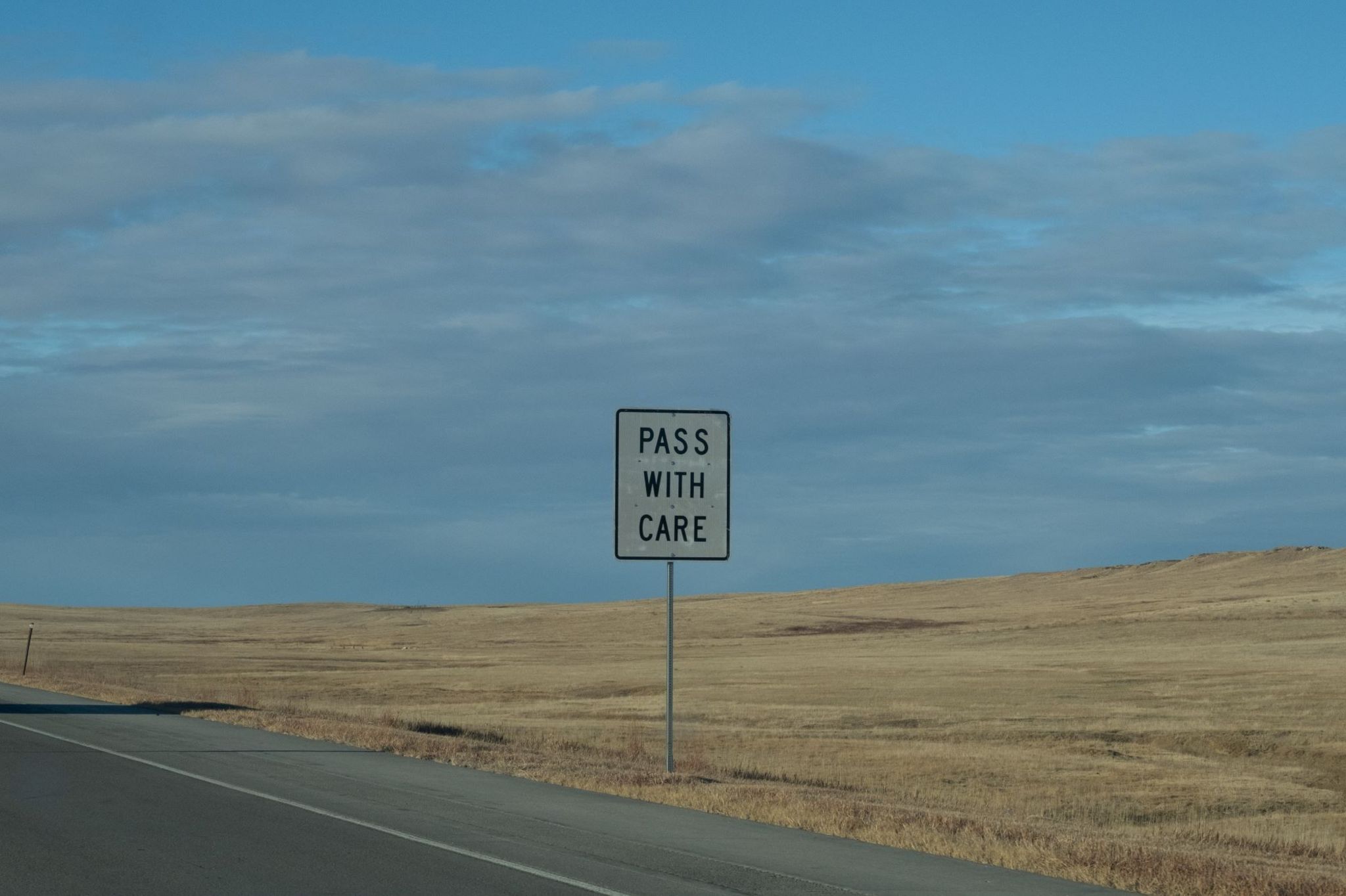 A sign beside the road, it reads Pass with care