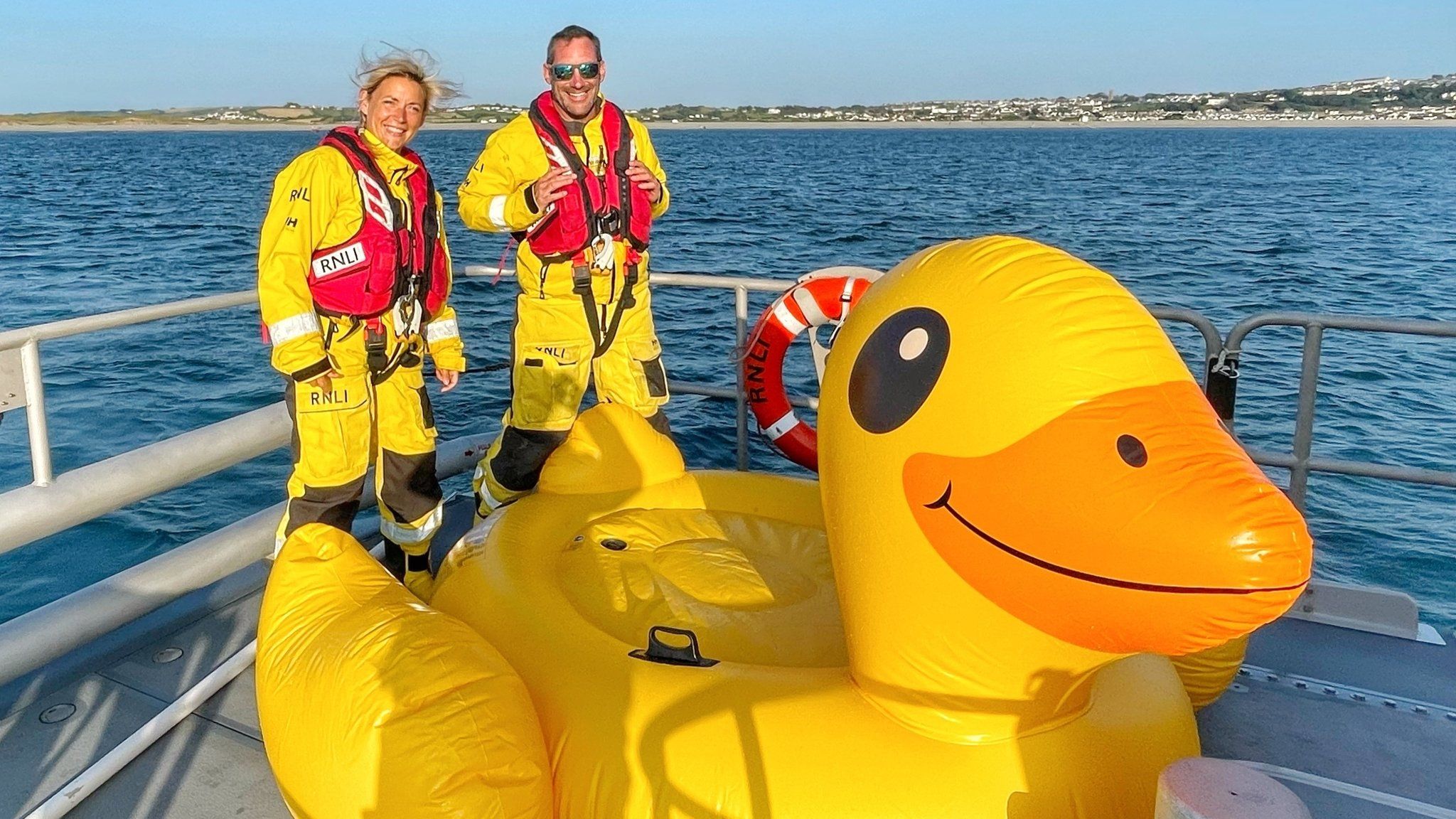 RNLI crew member with Quackers the inflatable duck on board a lifeboat