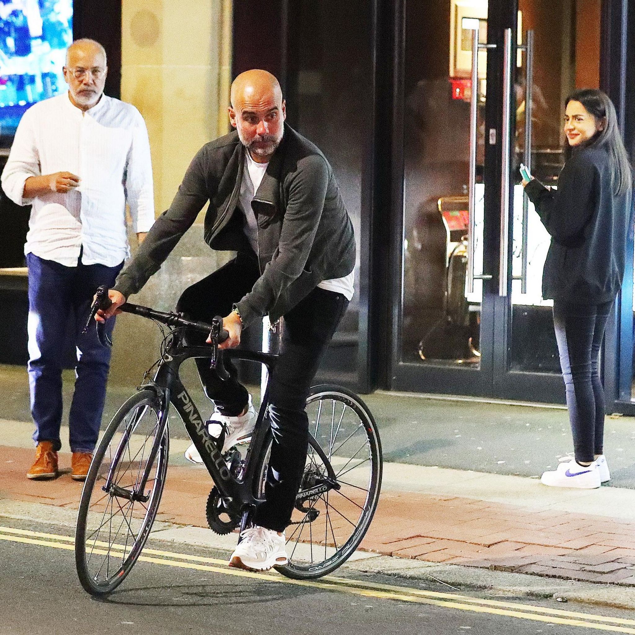 Pep Guardiola cycles away from a city-centre Manchester restaurant