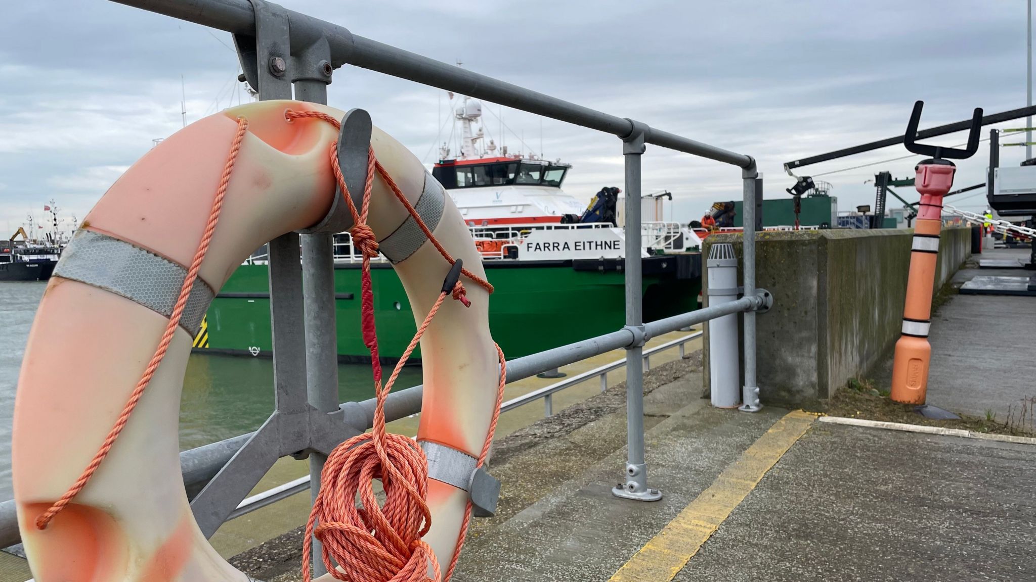 A life ring on the quayside at the Port of Lowestoft with a service vessel in the background