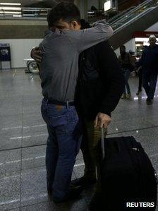 Glenn Greenwald and David Miranda embrace inside an airport