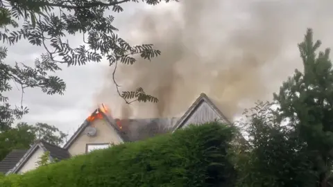 Flames and smoke come from the roof of a house in Aviemore