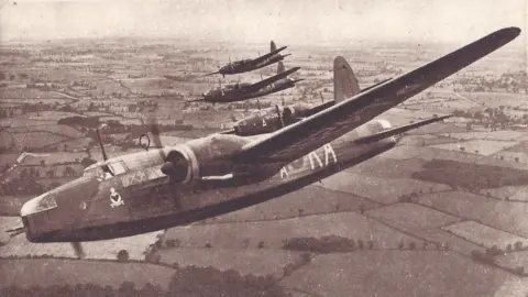 A black-and-white photo showing four Wellington bomber aircraft from IX Squadron based in Honington in formation, banking to their right. They are flying over fields