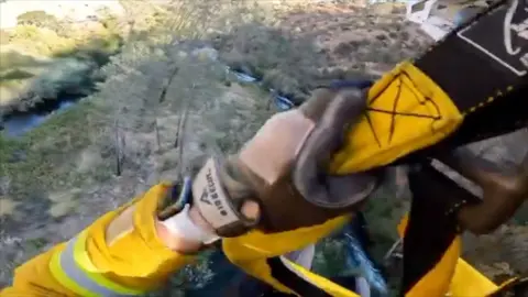 Rescuer holding on to helicopter 