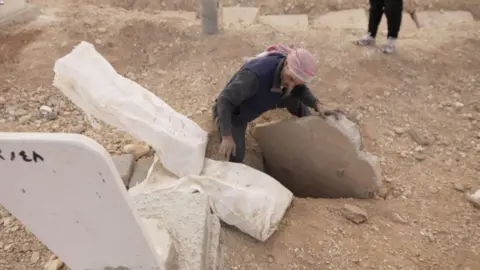 BBC A man searching through graves in Syria 