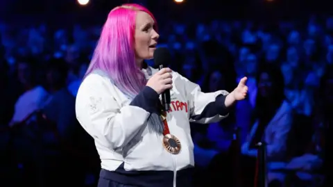 Getty Images for The National Lottery Jodie Grinham speaking with a microphone, wearing kit, at the event 