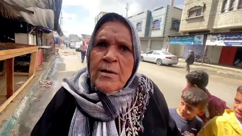 Woman speaking to camera with children behind her