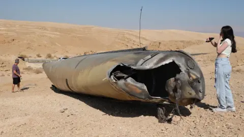 People check the wreckage of an Iranian ballistic missile outside the city of Arad, southern Israel