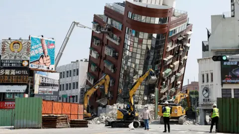 Workers carry out operations while on an elevated platform of a firefighting truck at the site where a building collapsed, following the earthquake, in Hualien, Taiwan, on 4 April 2024