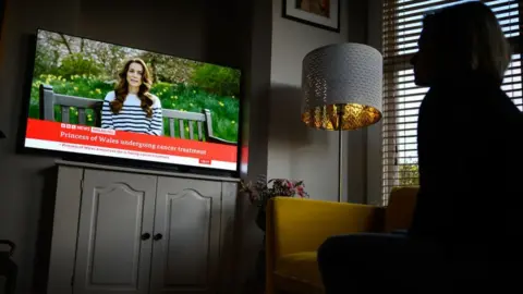 A woman watches Catherine on BBC News on a screen