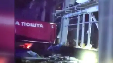 Lorry sits in front of building with windows blown out