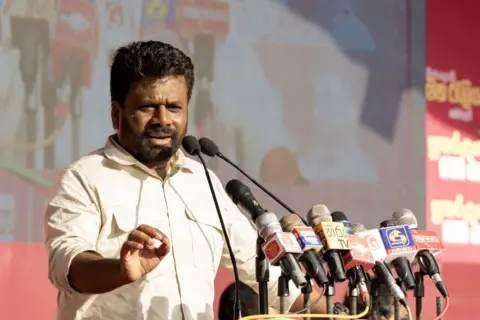 Anura Kumara Dissanayake speaks into an array of microphones