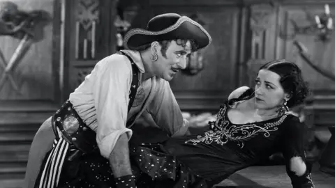 Alamy A still from a 1920s pirate film showing a male pirate menacing a woman