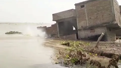 Building collapses into flooded river in India