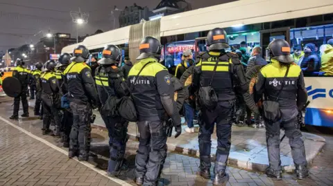 Police in riot gear guard a Dutch bus in Amsterdam